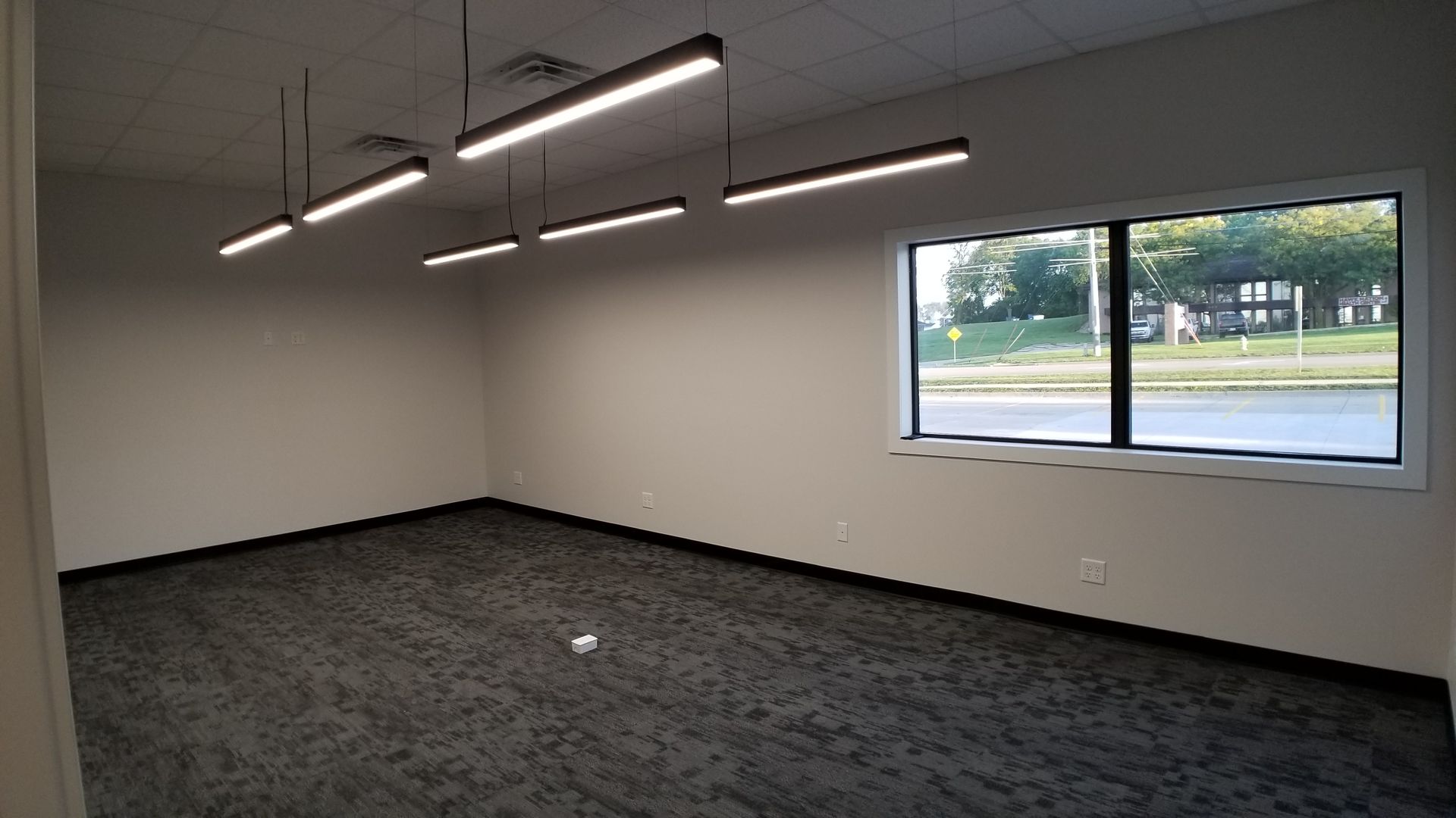 An empty room with a large window and a lot of lights hanging from the ceiling.