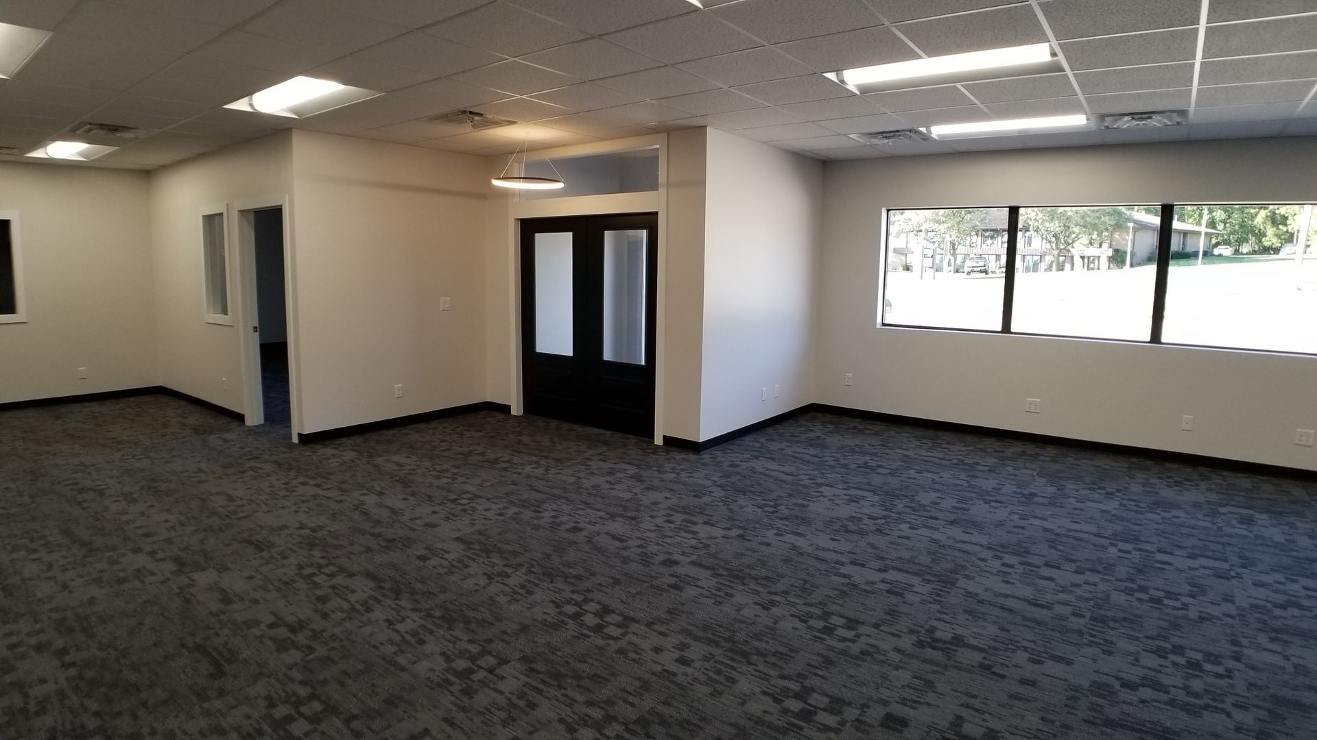 A large empty room with a carpeted floor and windows.