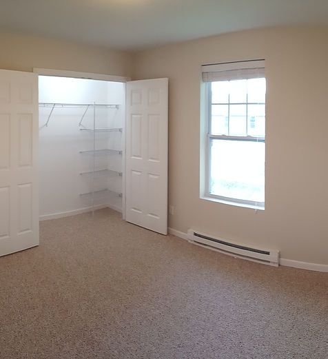 An empty bedroom with a closet and a window