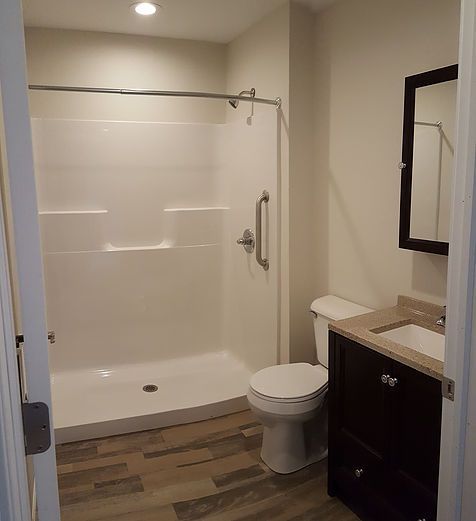 A bathroom with a toilet , sink , shower and mirror.