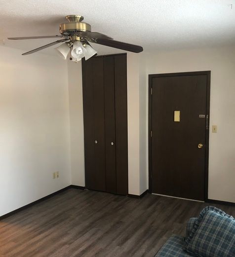 A living room with a ceiling fan and a door