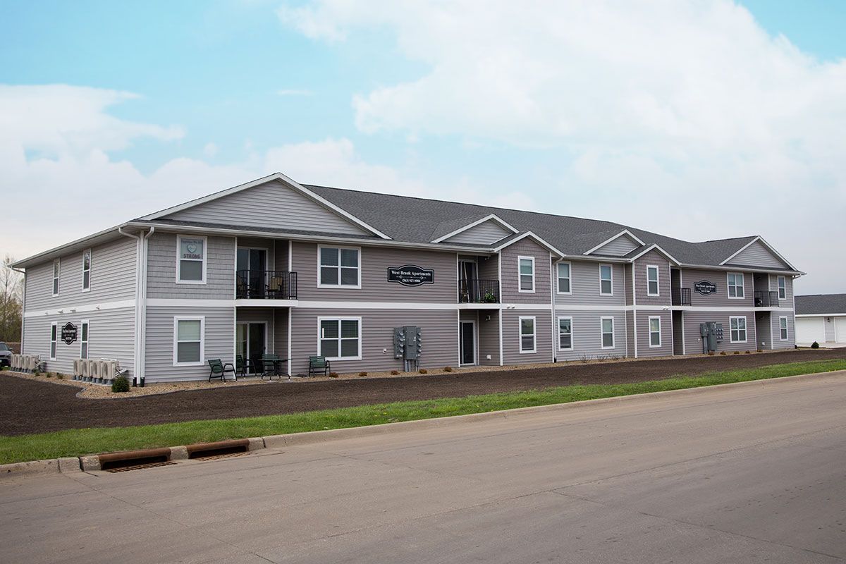 A large apartment building with a lot of windows is sitting on the side of the road.