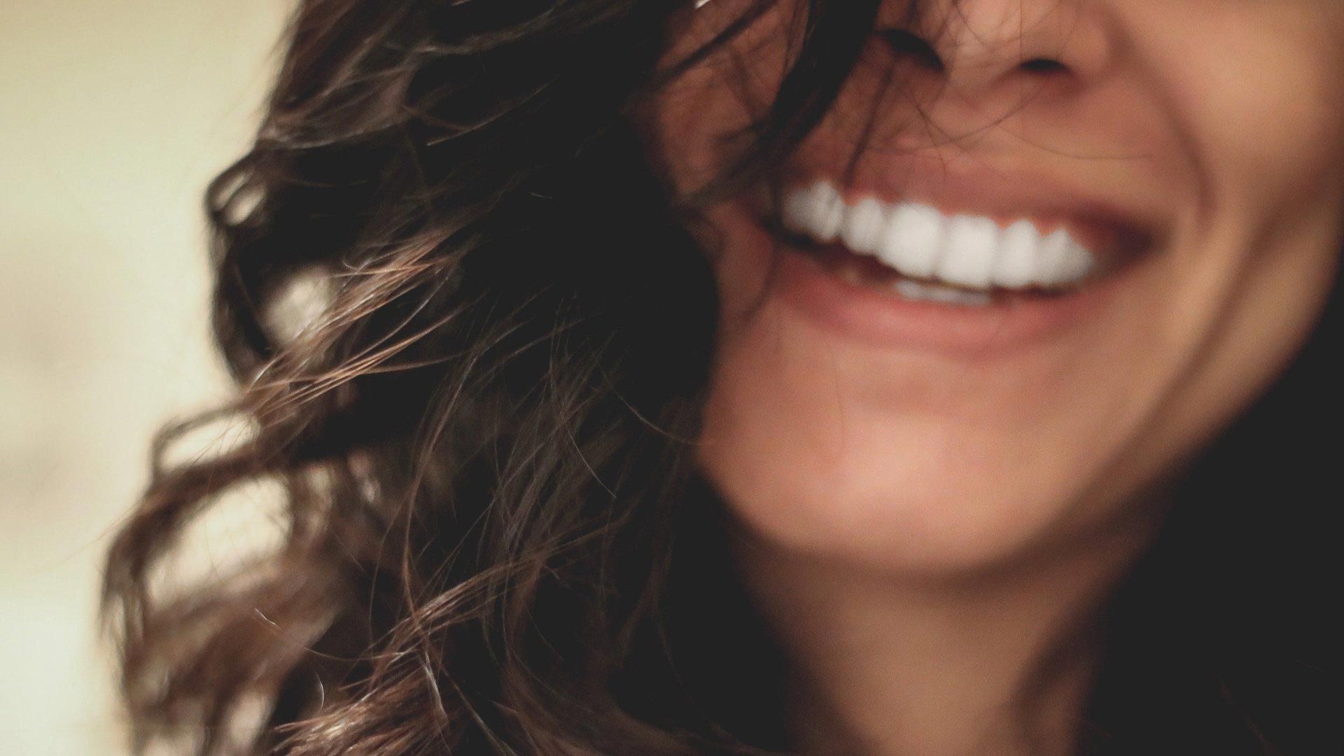 Frau lächelt mit hochwertigem Zahnersatz