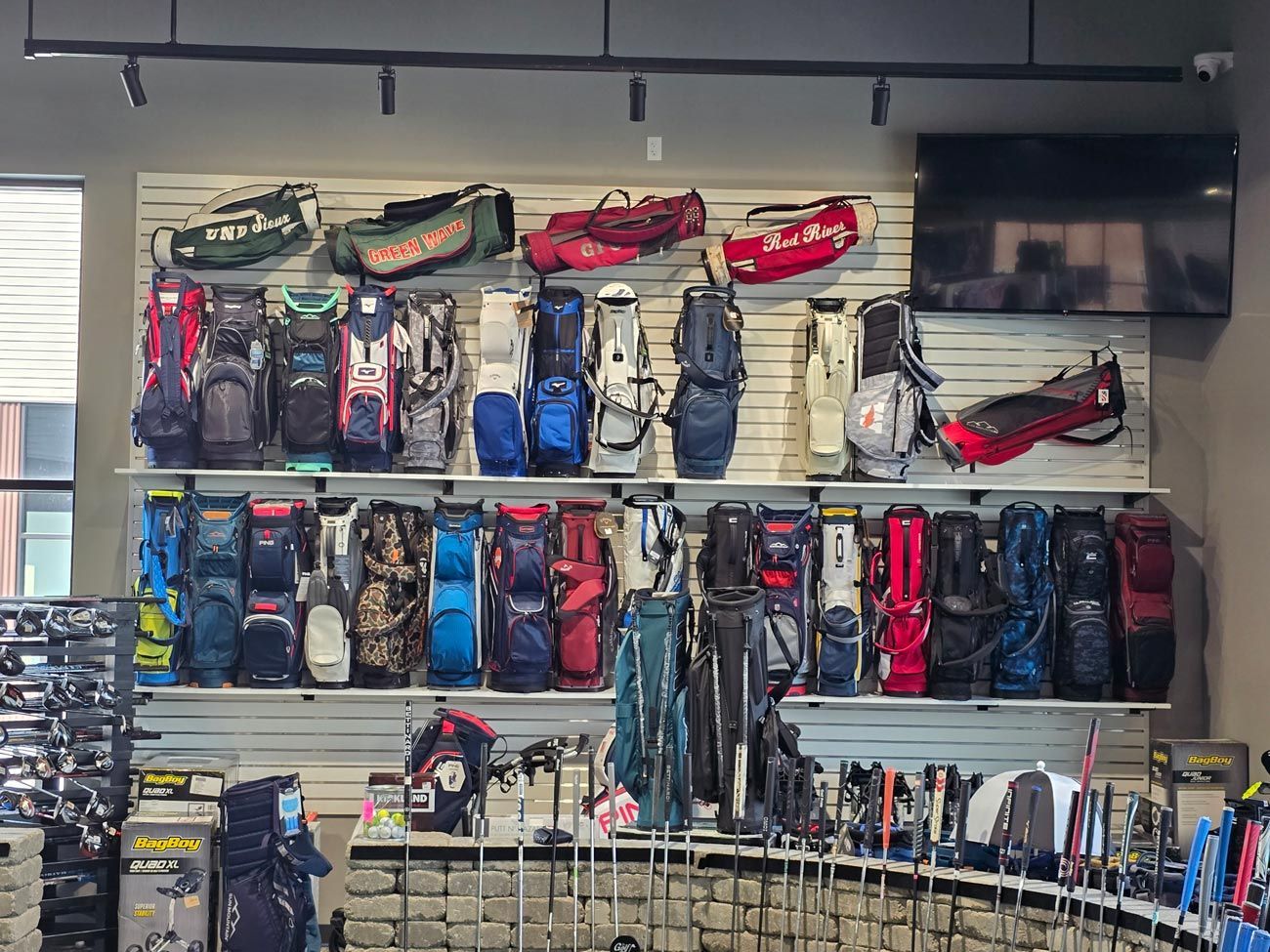 A wall filled with lots of golf bags and clubs in a store.