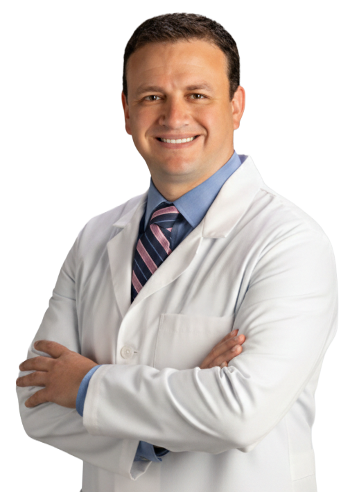 Man in a white lab coat with arms crossed, smiling, wearing a blue shirt and tie.