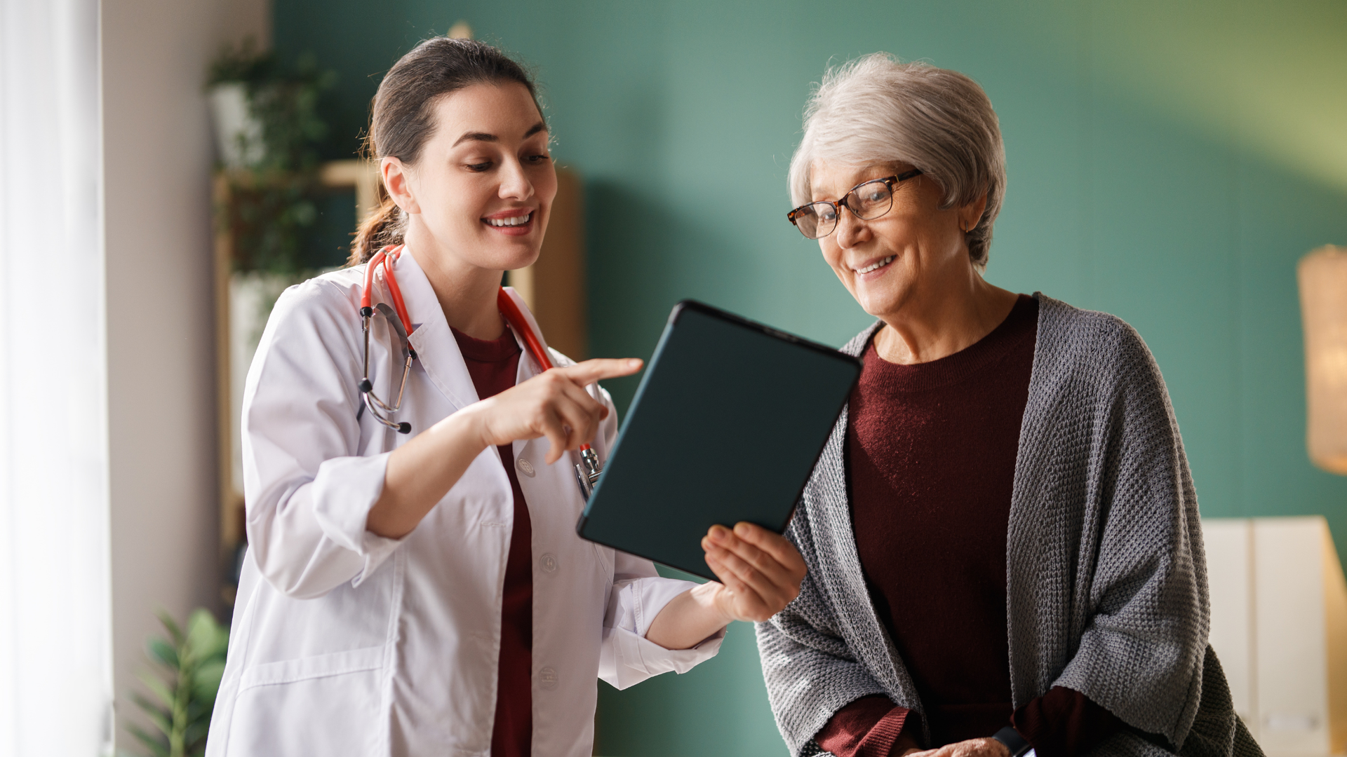 Doctor showing a smiling older patient a folder in a bright clinic office