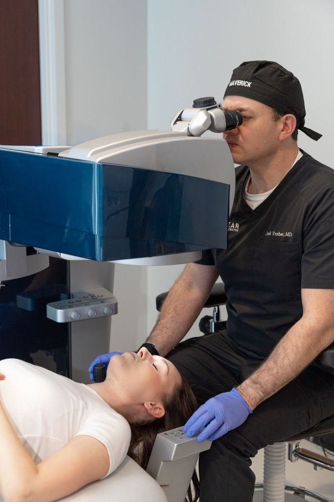 Doctor operating on a patient's eye with laser equipment in a medical office.