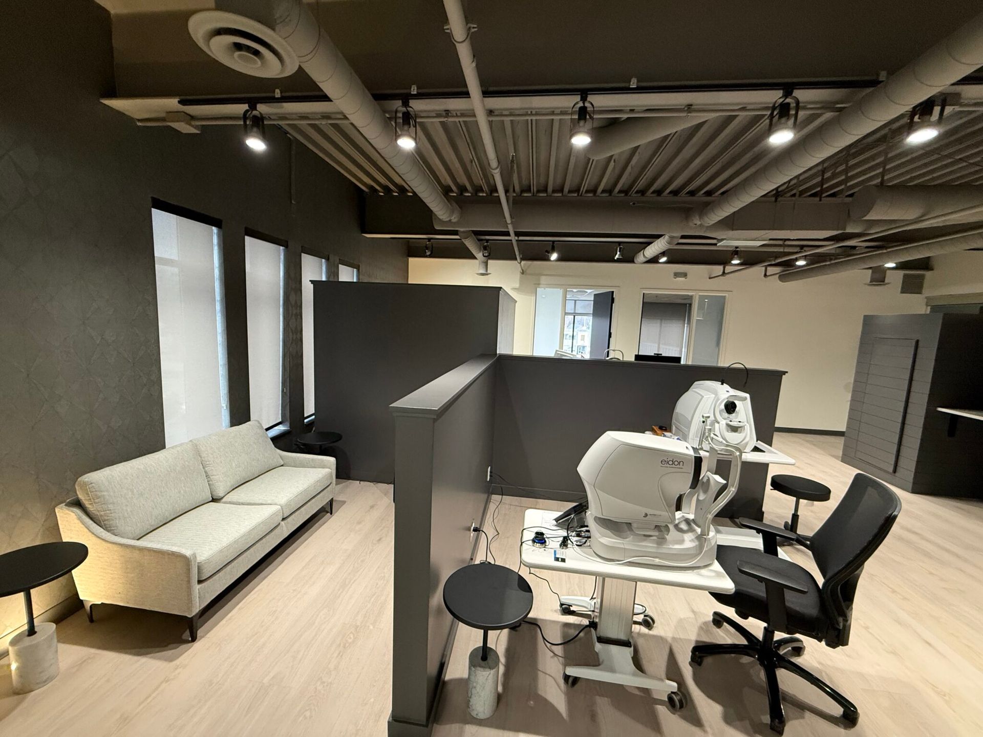 Modern office with lounge seating, desks, chairs, and exposed ceiling lights