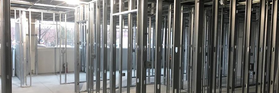 Interior construction site with exposed metal framing and unfinished walls in a bright hallway