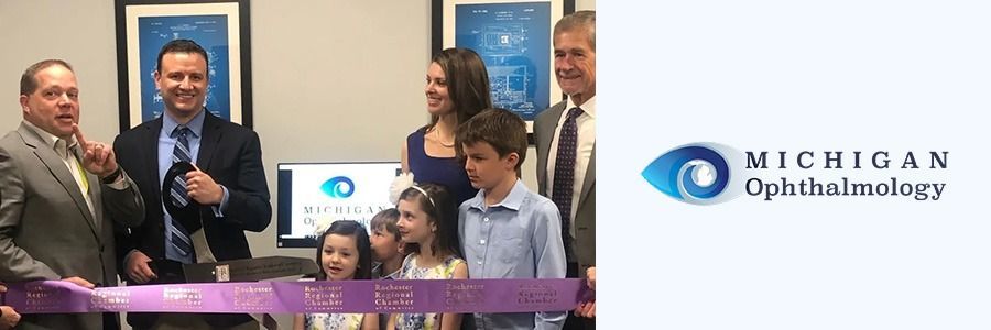 Ribbon-cutting ceremony at Michigan Ophthalmology with staff, balloons, and clinic logo backdrop
