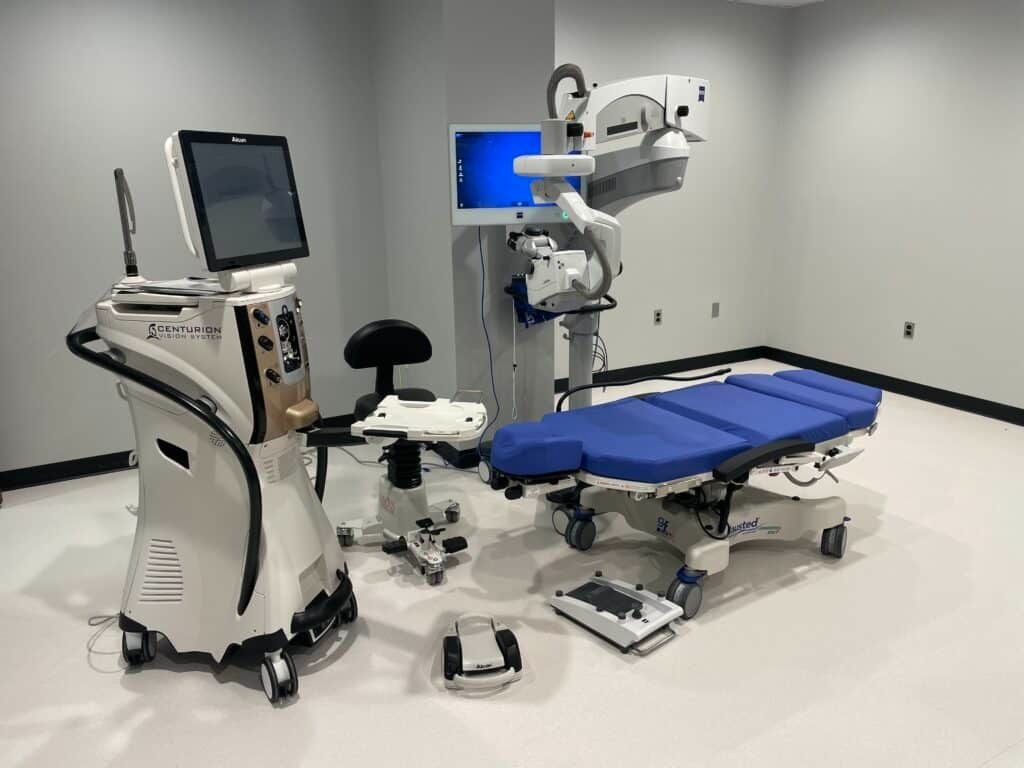 Hospital exam room with ultrasound machine, blue exam table, and medical equipment on a clean floor