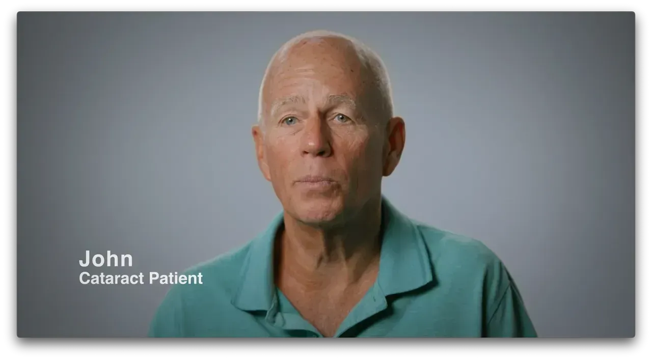 Portrait of John, a cataract patient, wearing a teal shirt against a gray background.