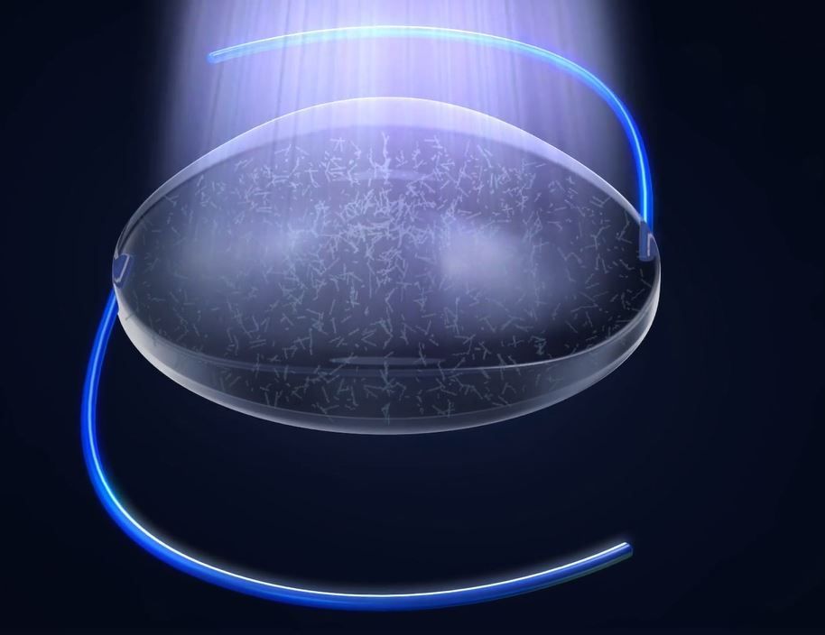 Woman smiling, blue sky background, wearing denim shirt and white tee.