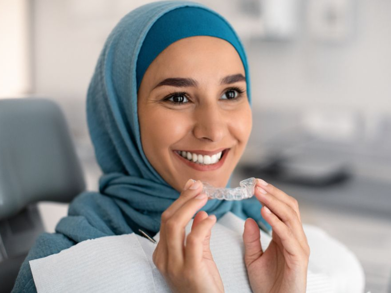 Senior woman in dentist chair looking at her teeth in a hand mirror.