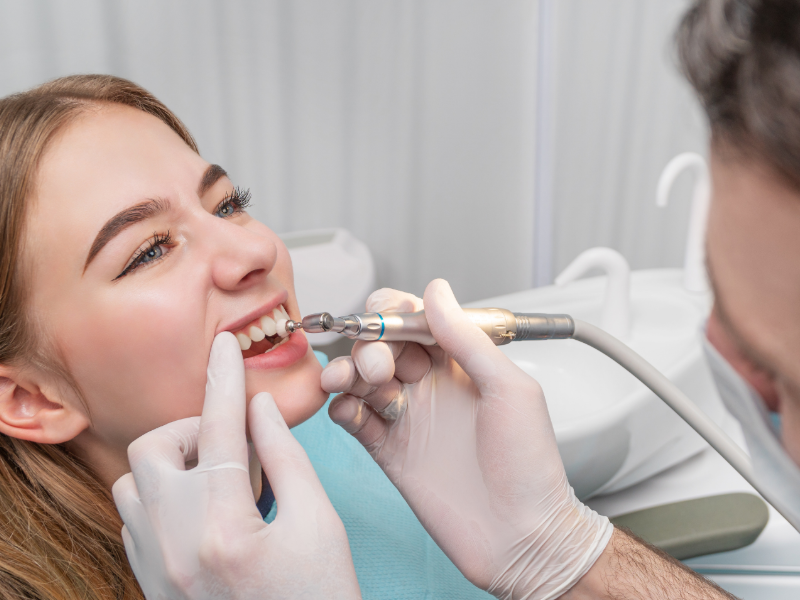 Dentist showing a patient his teeth with a mirror. Both are smiling.