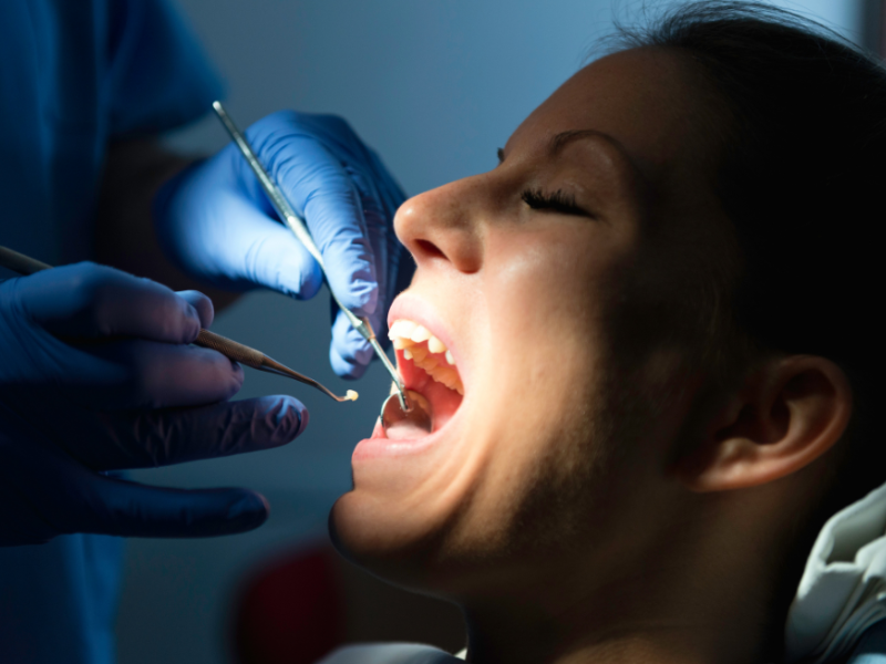 Senior woman in dentist chair looking at her teeth in a hand mirror.