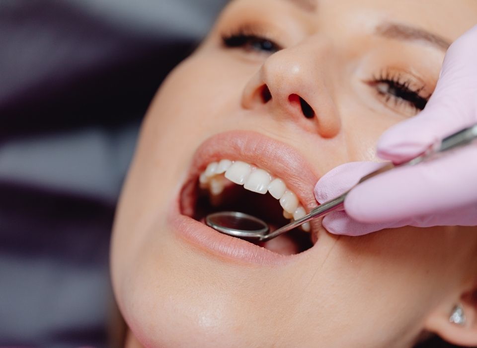 Smiling man in a dentist chair, giving a thumbs-up. He's in a clinic with dental equipment.