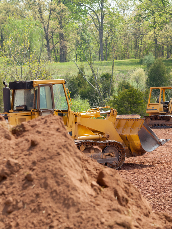 a small excavator is digging a hole in the dirt in a field .