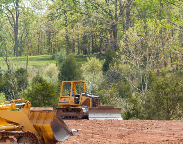 a dirt field with trees in the background on a sunny day