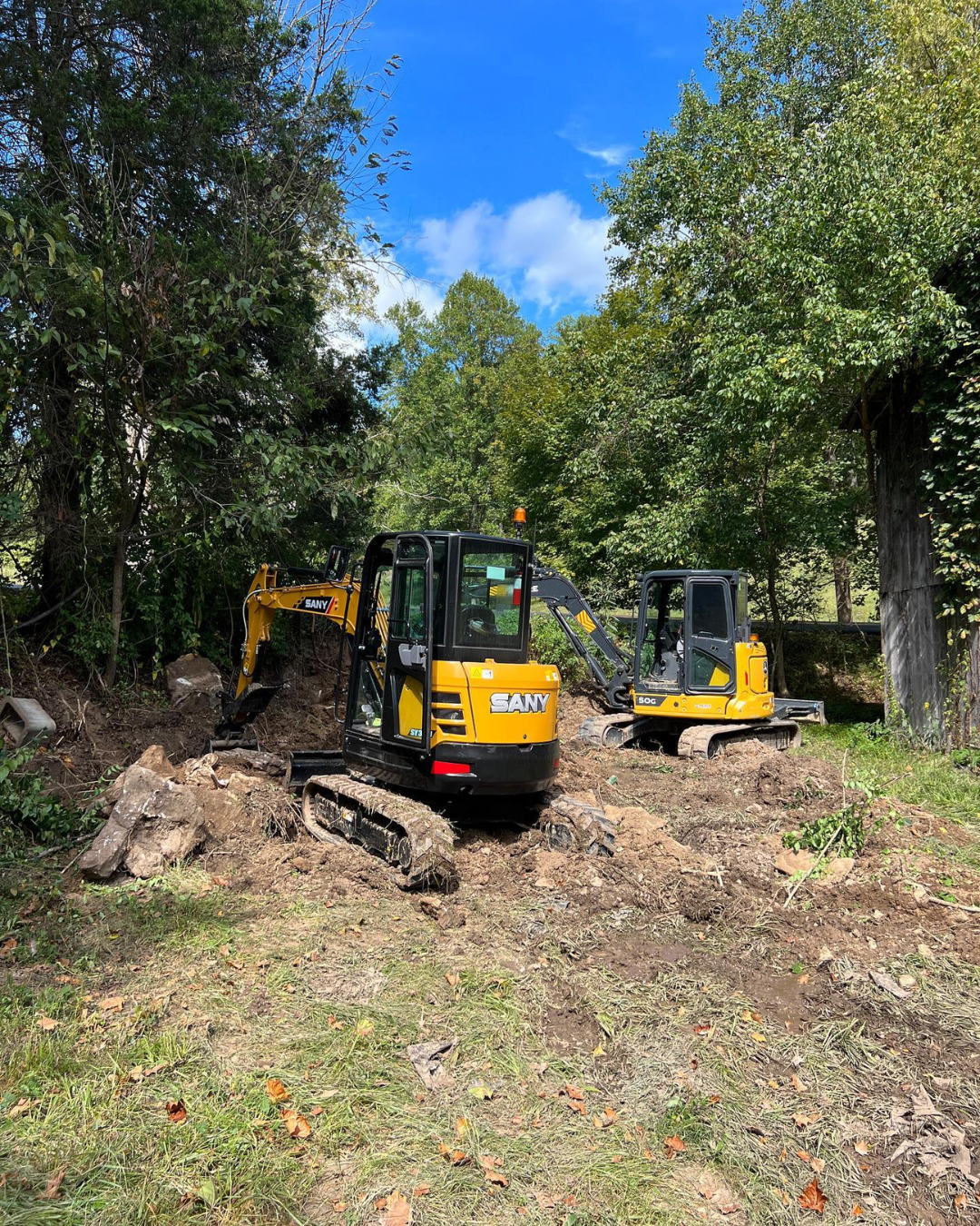 a small excavator is digging a hole in the dirt in a field .