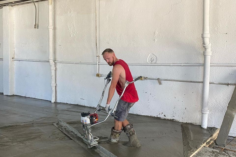 a man is using a machine to level a concrete floor .