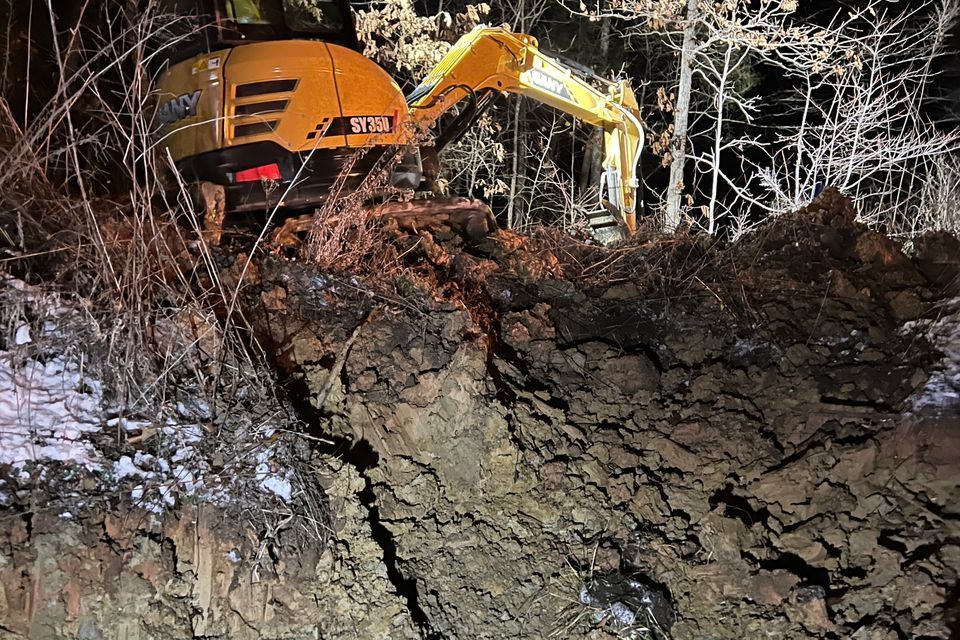 a small excavator is digging a hole in the dirt in a field .