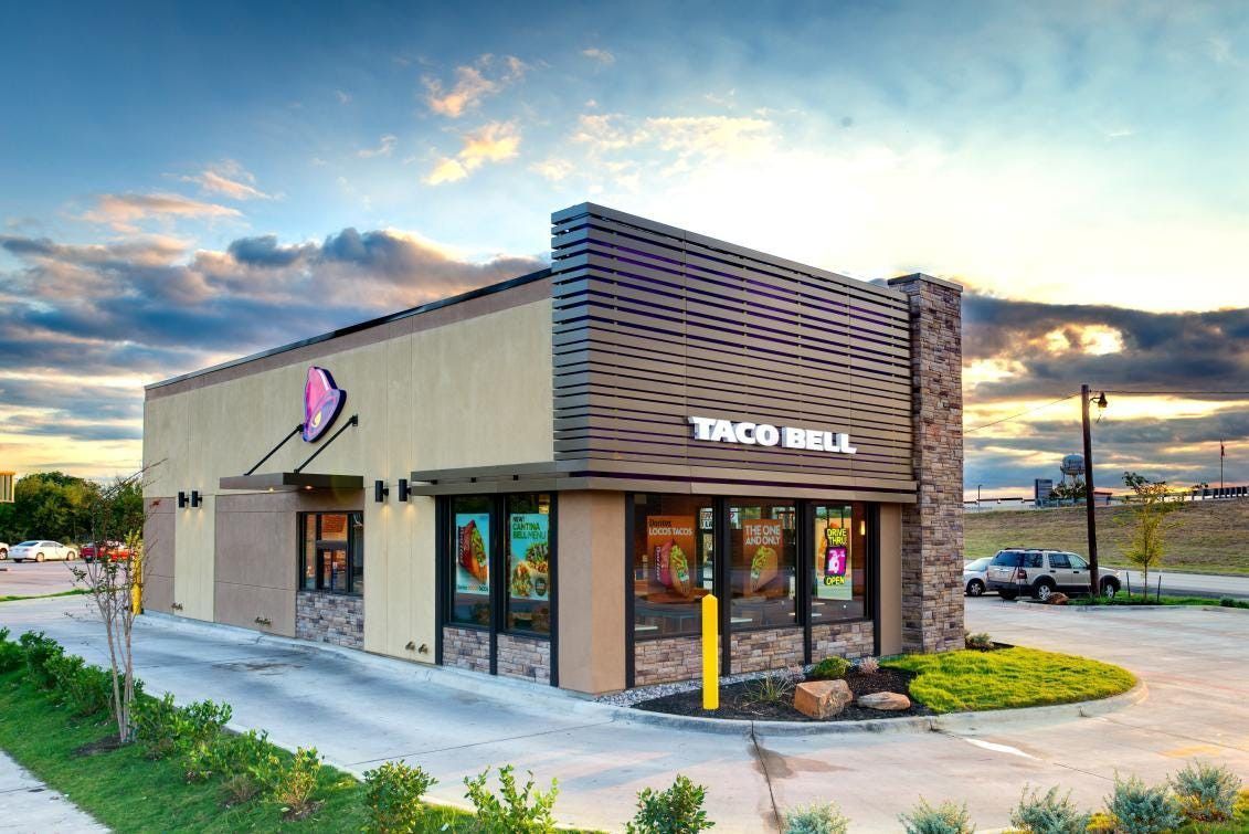 Taco Bell restaurant with drive-thru and beige facade against a partly cloudy sky.
