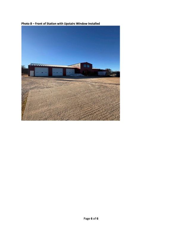 Front view of a building with three garage doors and a gravel driveway under a blue sky.