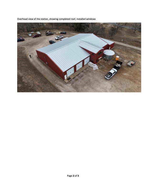 Overhead view of a red and silver metal building with cars and trucks, in an outdoor setting.