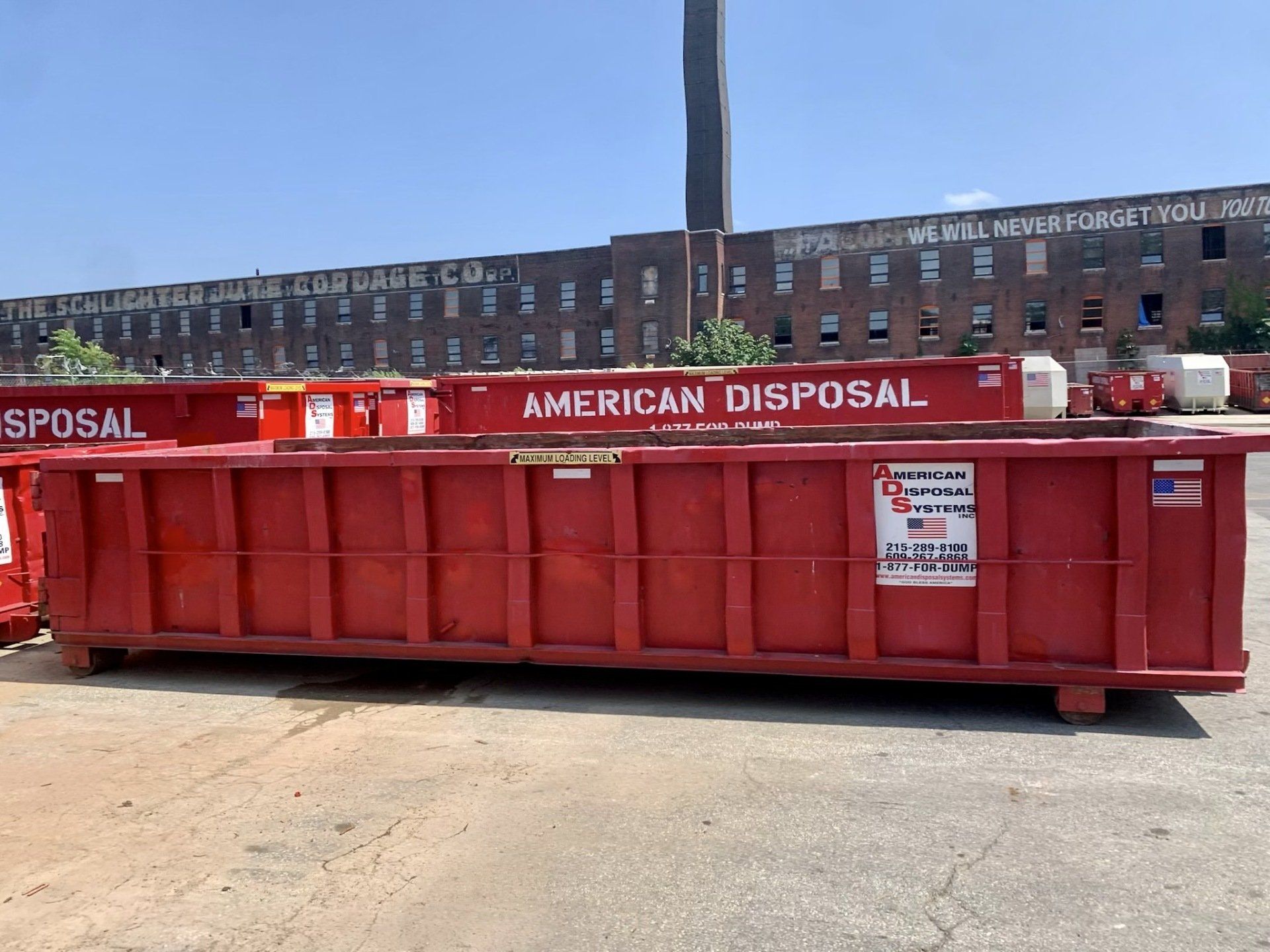 A red, twenty cubic yard dumpster is in a parking lot