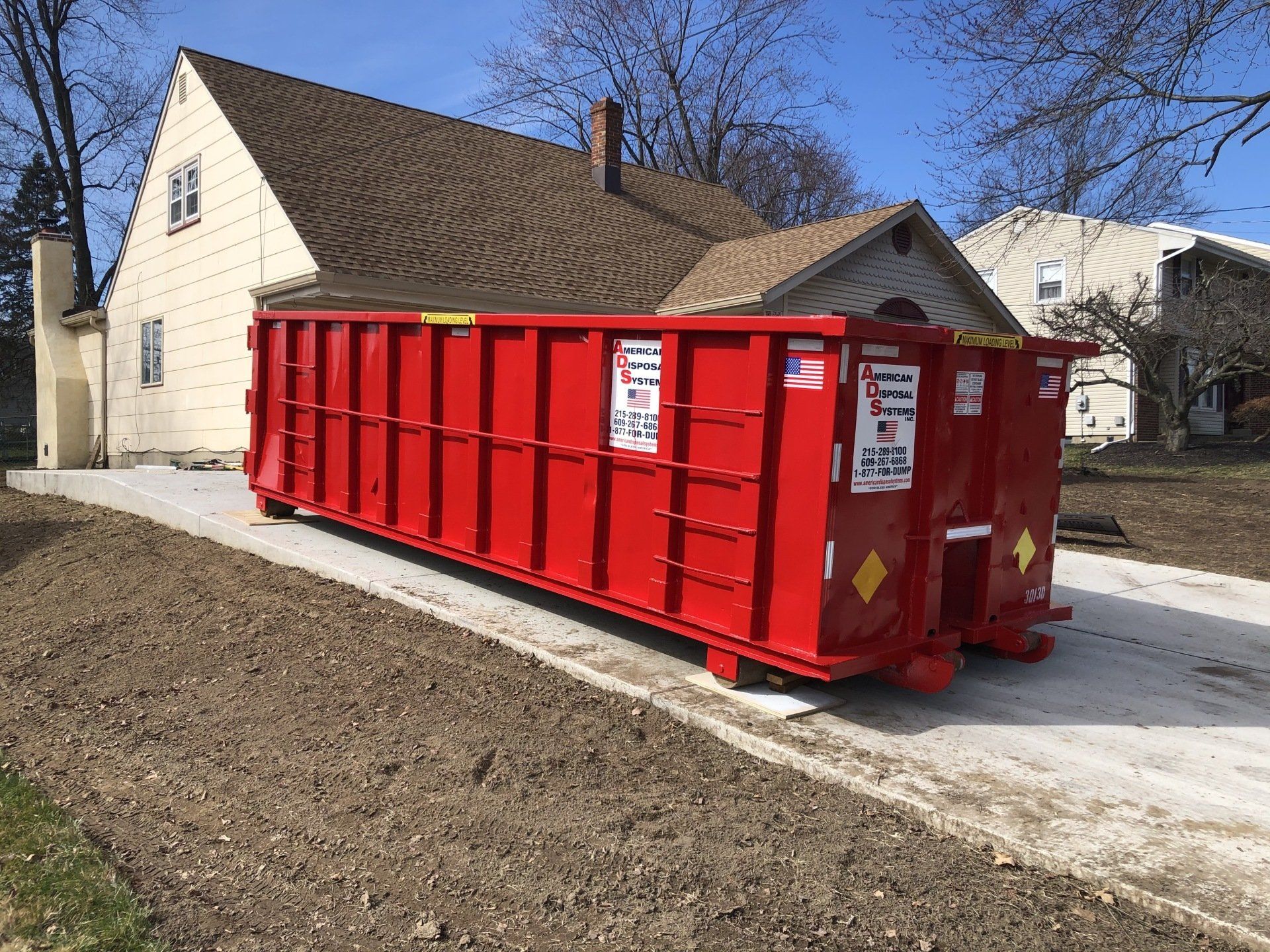 A thirty cubic yard dumpster is parked in the driveway of a home