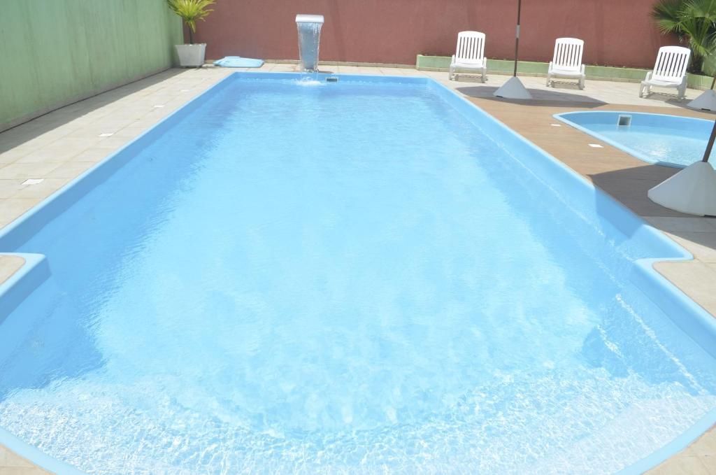 Uma grande piscina cercada por cadeiras e guarda-sóis