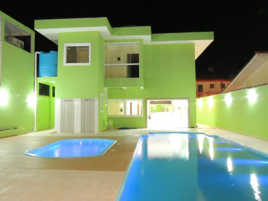 Uma casa verde com uma piscina na frente