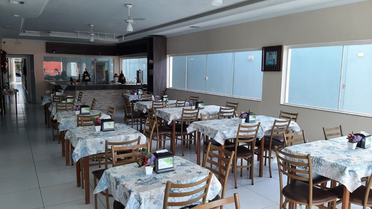 Um restaurante com mesas e cadeiras e uma grande janela.