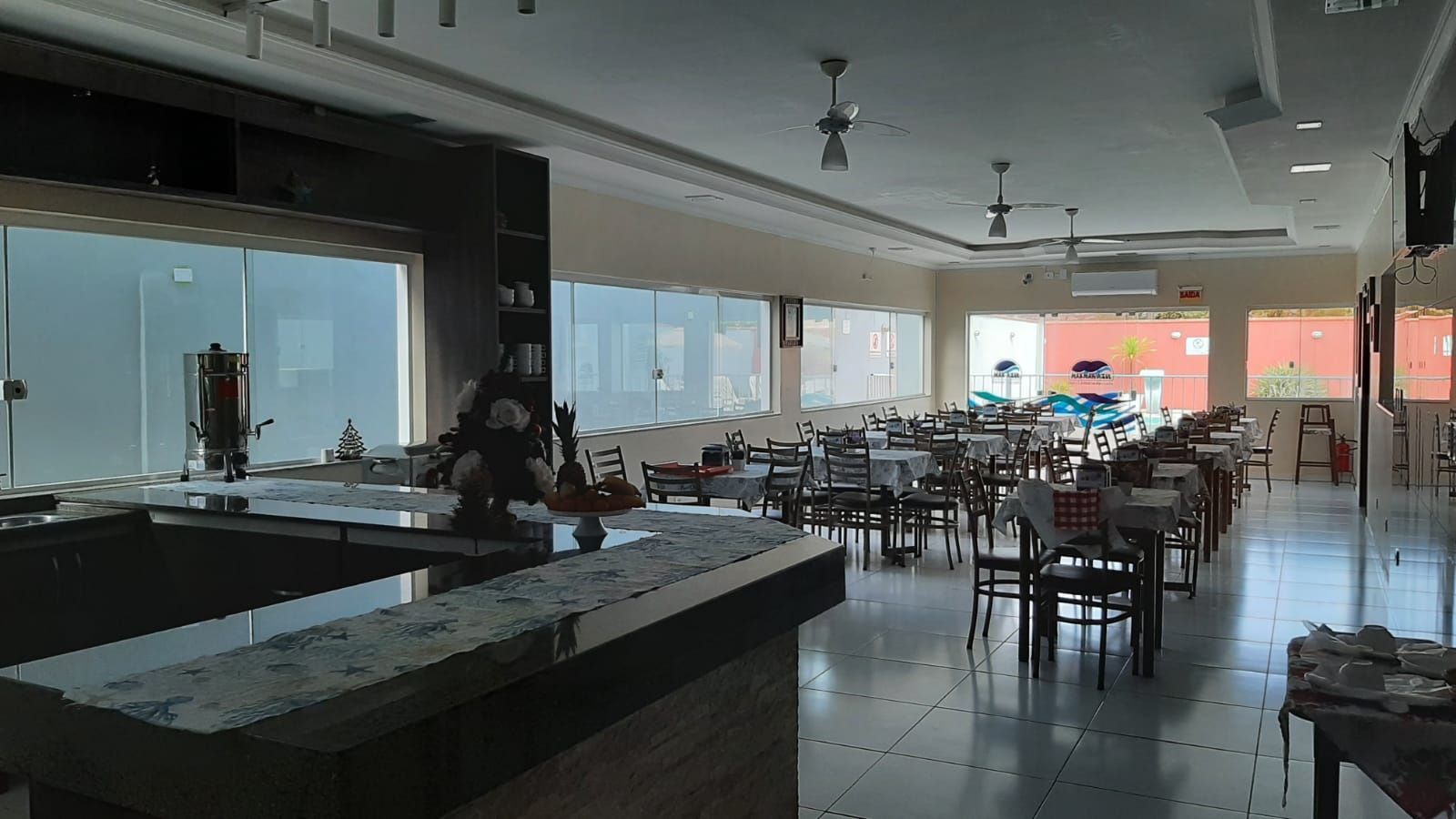 Uma grande sala de jantar com mesas e cadeiras e um bar.