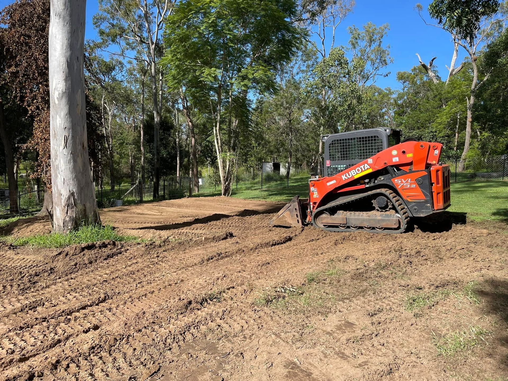 A red and black bulldozer is driving through a dirt field. — Upgrade Earthworks In South Kolan, QLD