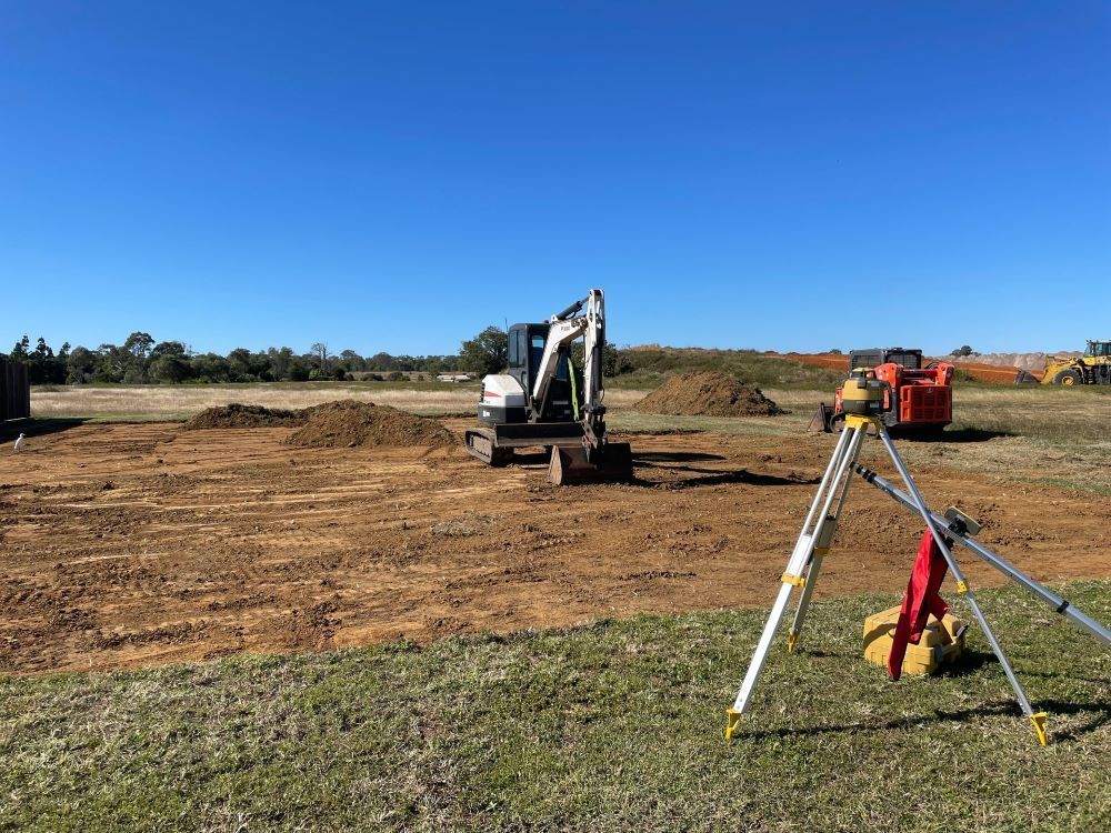 A Construction Site With a Bulldozer and a Tripod in the Foreground — Upgrade Earthworks In South Kolan, QLD