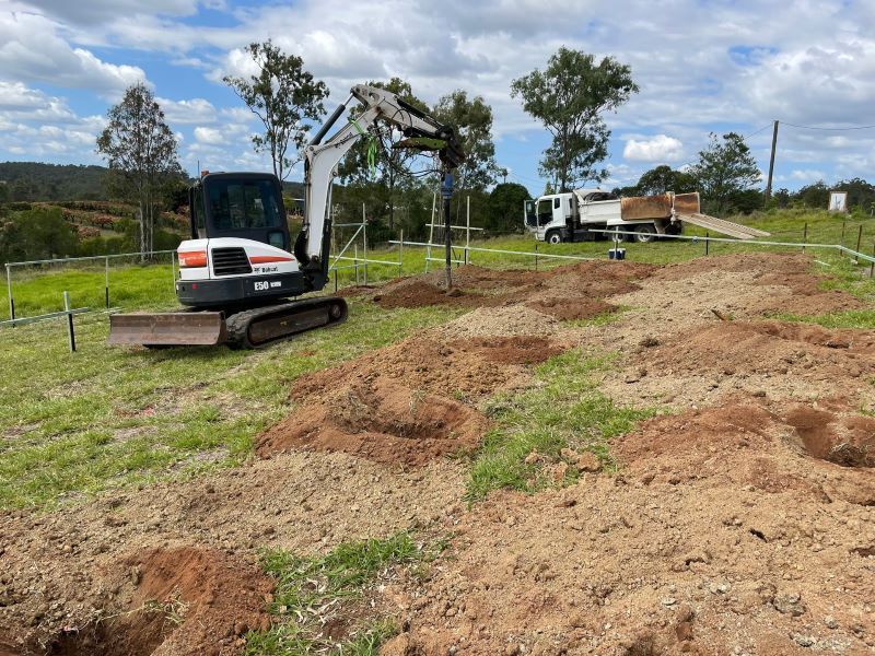 A Small Excavator is Digging a Hole in the Dirt in a Field — Upgrade Earthworks In South Kolan, QLD