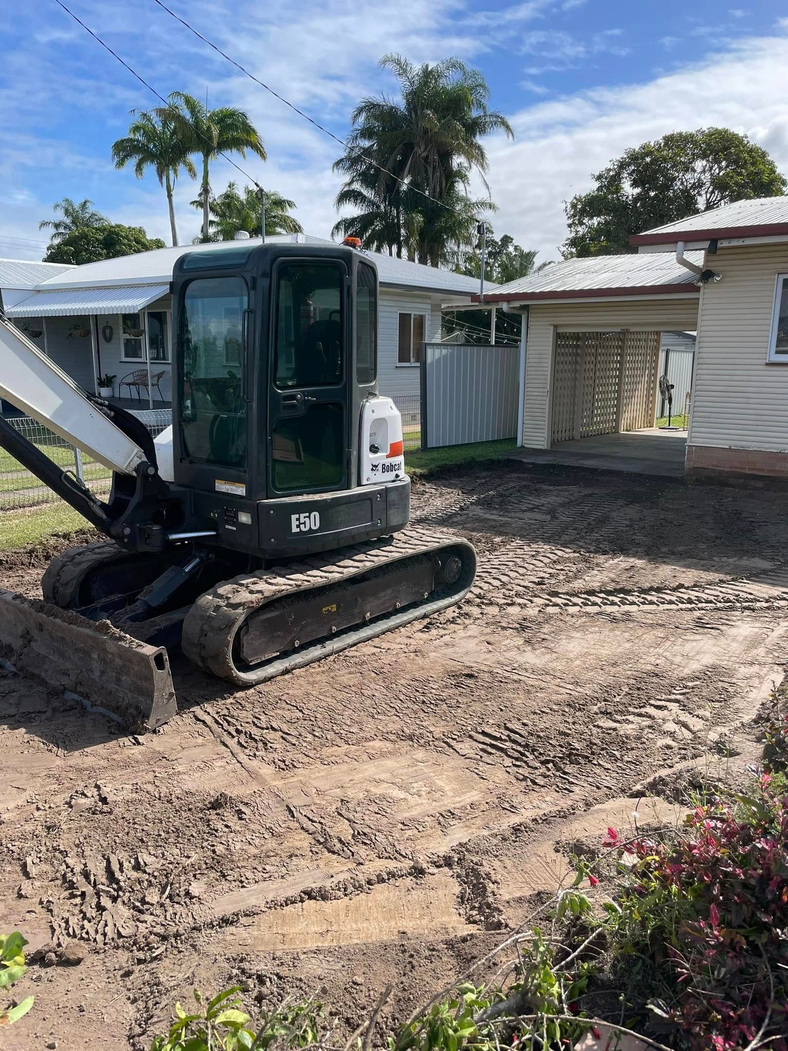 A small excavator is sitting in the dirt in front of a house. — Upgrade Earthworks In South Kolan, QLD