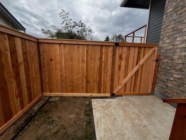 A wooden fence with a gate in front of a brick building