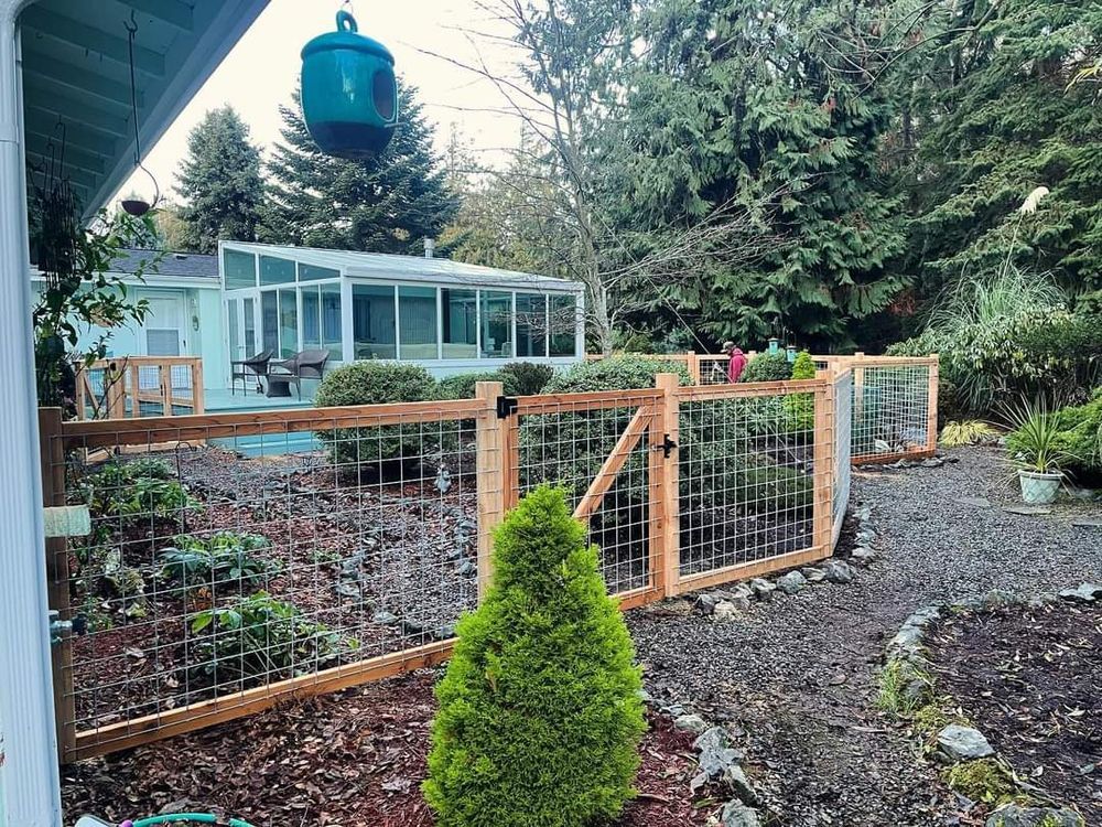 A wooden fence surrounds a garden in front of a house.