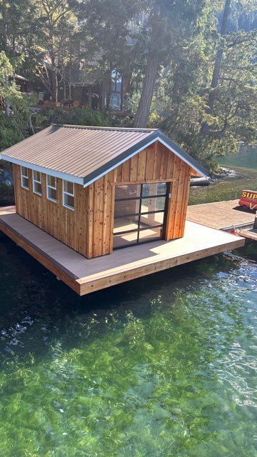 A small wooden house is sitting on top of a dock next to a body of water.