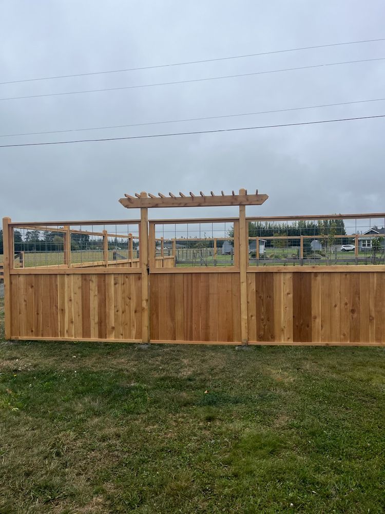 A wooden fence with a pergola attached to it is sitting on top of a lush green field.