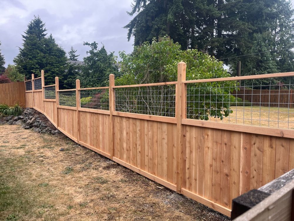 A wooden fence with a wire fence in the backyard.