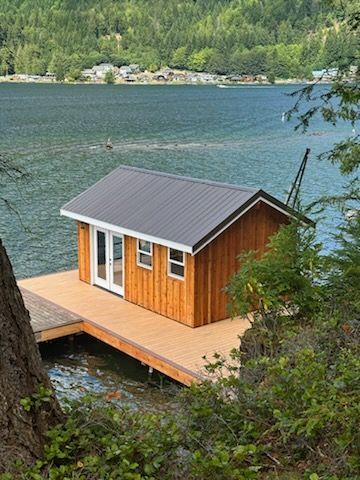 A small wooden house is sitting on a dock overlooking a lake.