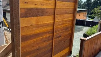 A wooden fence is being built in a backyard.