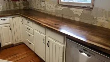 A kitchen with white cabinets and a wooden counter top.