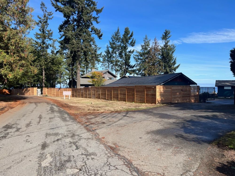 A wooden fence surrounds a house on the side of a road