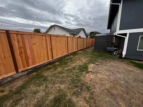 A wooden fence is in the backyard of a house.