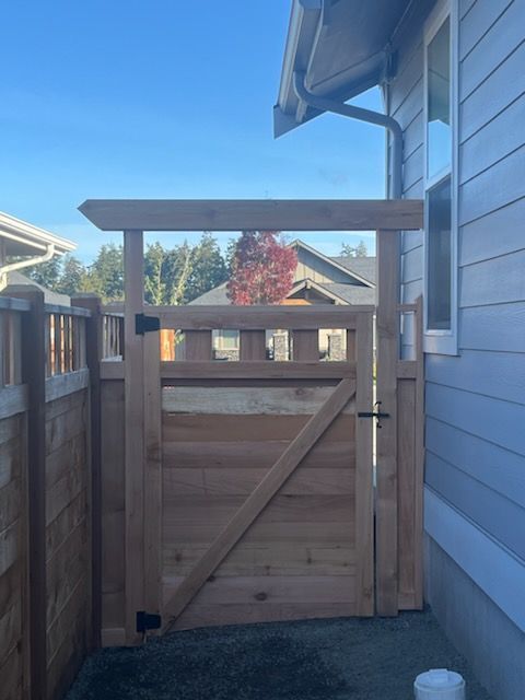 A wooden gate is between a fence and a house